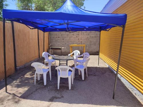 a table and chairs under a blue umbrella at Granja Vip Valle de Elqui in Vicuña