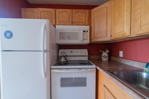 a kitchen with a white refrigerator and white microwave at 19th Hole Condo in Kahuku