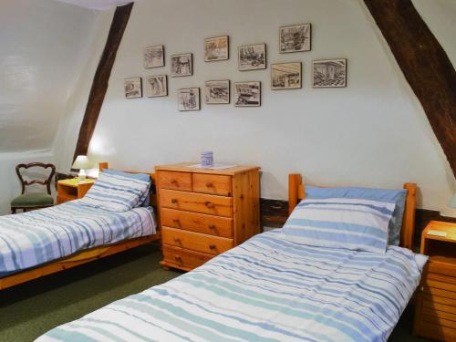 two beds in a room with pictures on the wall at October Cottage in Collingbourne Kingston