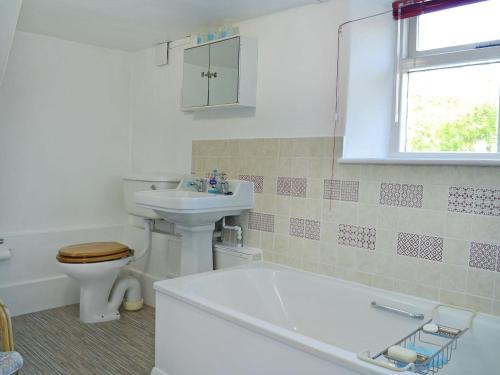 a bathroom with a toilet and a tub and a sink at October Cottage in Collingbourne Kingston