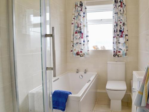 a bathroom with a tub and a toilet and a window at Craigneish Bungalow in Trearddur