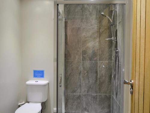 a bathroom with a shower with a toilet and a glass door at Moors Rest in Sculthorpe