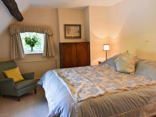 1 dormitorio con 1 cama, 1 silla y 1 ventana en Rose Cottage No2 - 28440 en Chipping Campden