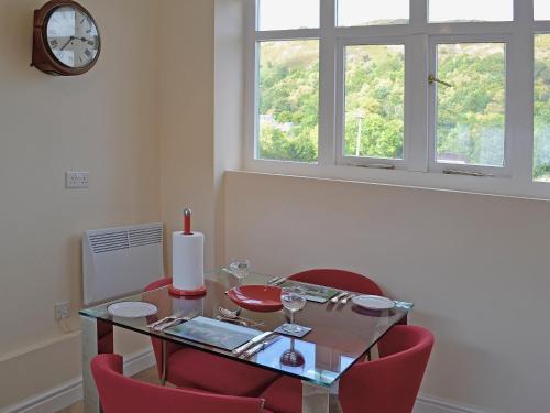 a dining room with a glass table and red chairs at Porters Lodge in Glyn-Dyfrdwy