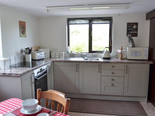 a kitchen with white cabinets and a sink and a window at Addylea - 16312 in Bowland Bridge