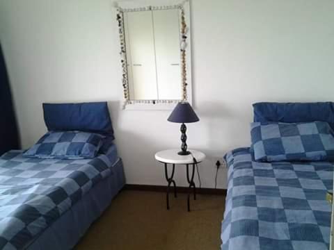 a bedroom with two beds and a table with a lamp at Swansnes in Stilbaai