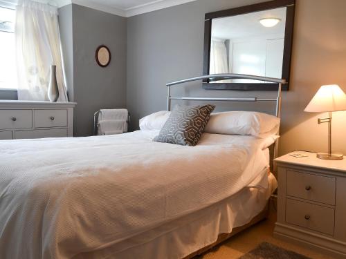 a bedroom with a large white bed with a mirror at Llys Aled in Llanedwen