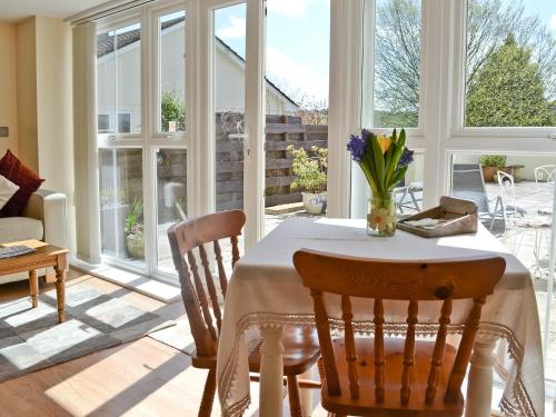 a dining room with a table and chairs and windows at The Little House in Calstock