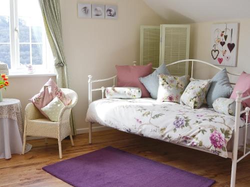 1 dormitorio con cama blanca con almohadas y alfombra morada en The Little House, en Calstock
