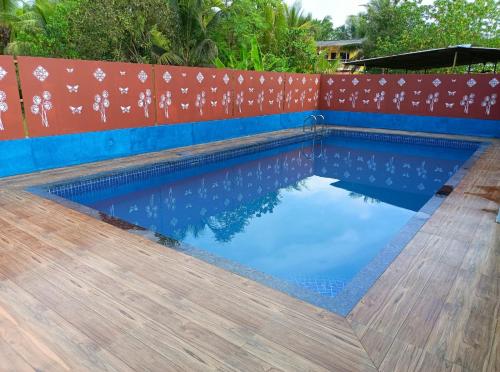 una piscina con pavimento in legno e recinzione di Shree Vighnaharta Cottage ad Alibaug
