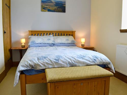 蘭戈倫的住宿－Bwthyn Clyd，一间卧室配有一张床,两台桌子上放着两盏灯