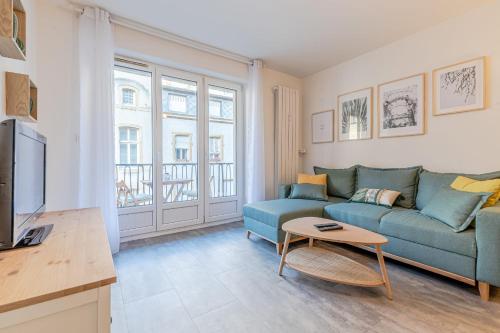 un salon avec un canapé bleu et une télévision dans l'établissement Casa Pestana, à Metz