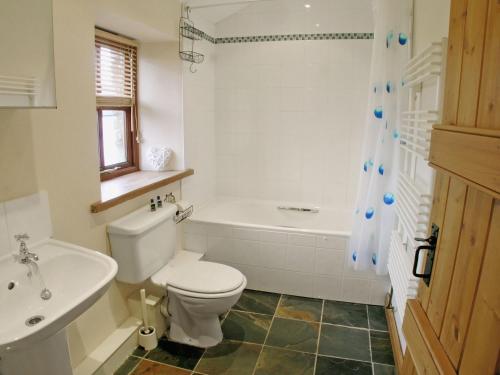 a bathroom with a toilet and a tub and a sink at The Hayloft in Great Ormside