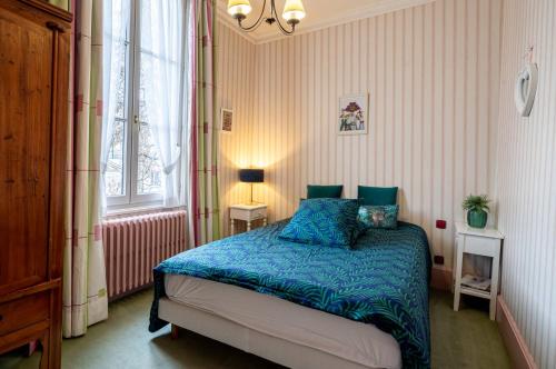 a bedroom with a bed with blue sheets and a window at Le Cedre Bleu in Bourges