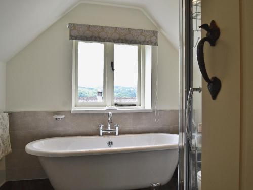 a bath tub in a bathroom with a window at Post Office Cottage in Highpeak Junction
