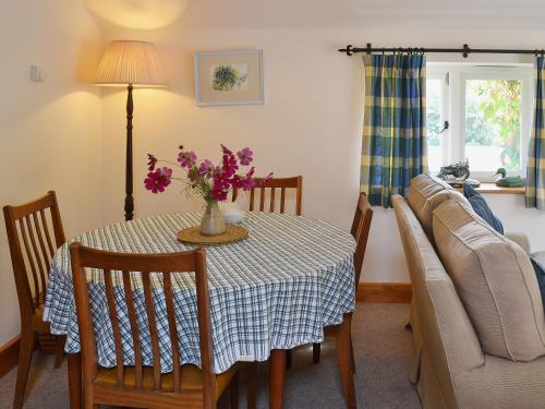 a dining room with a table and a couch at Bluebell Cottage in Alburgh