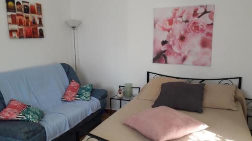 - un salon avec un canapé bleu et un oreiller rose dans l'établissement Gite au calme la mignonne, à Grimaud