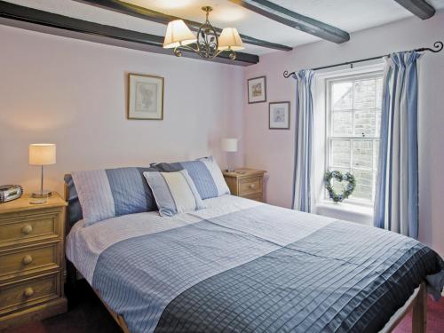 a bedroom with a blue bed and a window at Sharrowhead Cottage - E4044 in Robin Hood's Bay