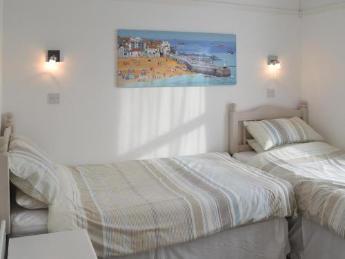 a bedroom with two beds and a painting on the wall at Polmeor in Polzeath
