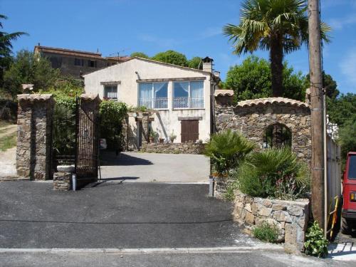 een stenen huis met een poort en een palmboom bij Gite sur les collines de mandelieu in Tanneron