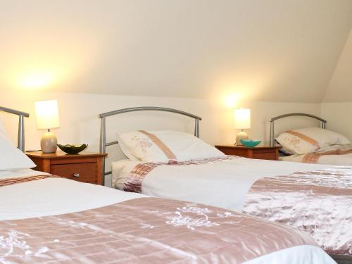 two beds in a room with two lamps on tables at Swallow Cottage in Shanklin