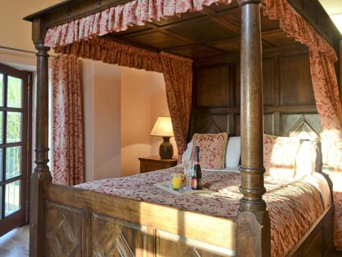 a wooden canopy bed with a tray of drinks on it at The Stables- Osb in Penbryn