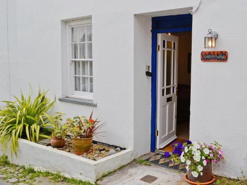 Casa blanca con puerta azul y macetas en Sundowners, en Calstock