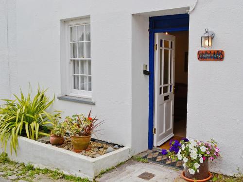 a white house with a blue door and potted plants at Sundowners in Calstock