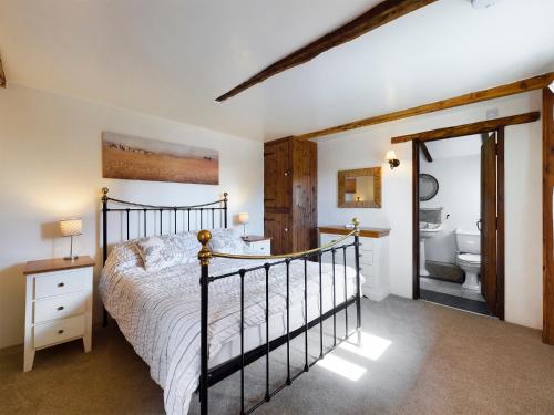 a bedroom with a bed and a bathroom at The Old Coach House in Iddesleigh