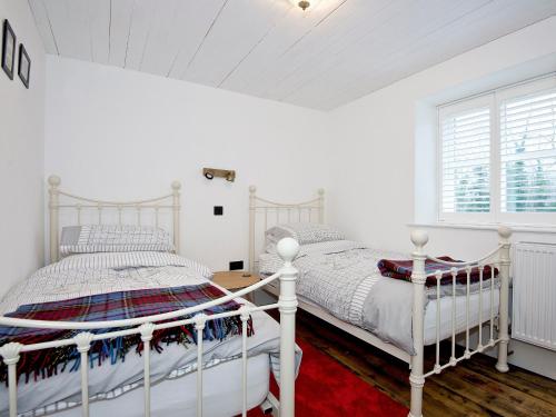 sypialnia z 2 białymi łóżkami i oknem w obiekcie Ty Cai w mieście Llanwnda