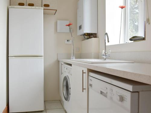 Coach House في ويرهام: مطبخ أبيض مع حوض وثلاجة