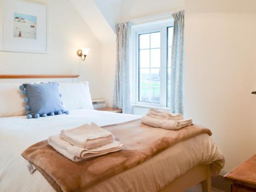a bedroom with a bed with towels on it at St Cadoc Cottage in Saint Merryn