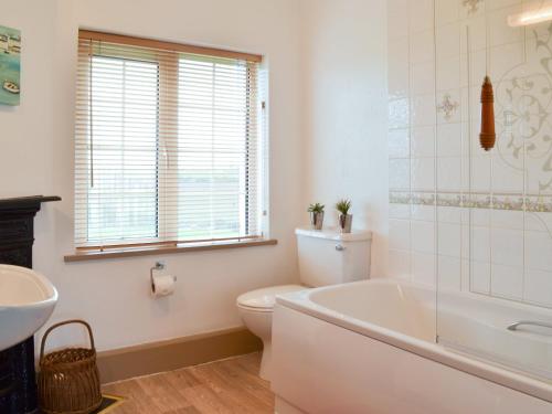 y baño con bañera, aseo y lavamanos. en St Cadoc Cottage, en St Merryn