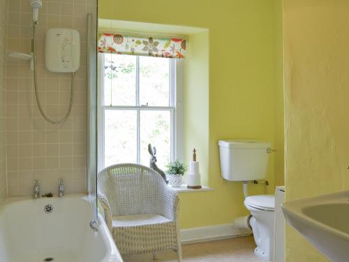 a bathroom with a tub and a toilet and a window at 3 Highrake in Glenridding