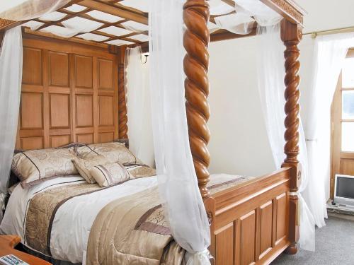 a bedroom with a wooden canopy bed with curtains at Stable Cottage in Burythorpe