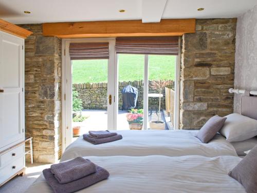 a bedroom with two beds and a stone wall at Appleshine Cottage in Almondbury