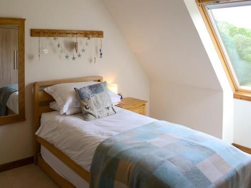 a bedroom with a bed with a pillow and a window at Allt Beag little Streams in Kishorn