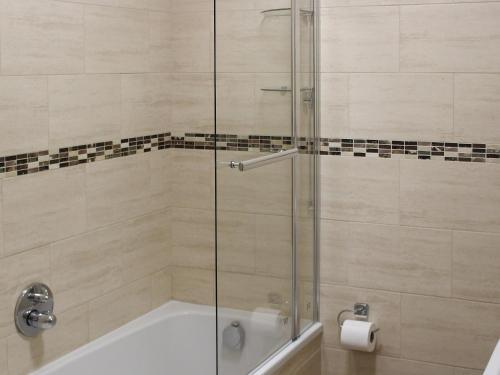 a shower with a glass door and a bath tub at Apartment 2 in Filey