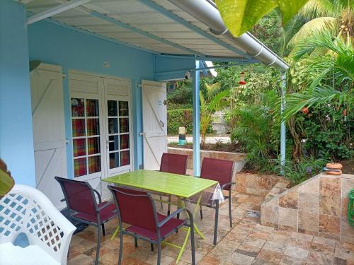 eine Terrasse mit einem grünen Tisch und Stühlen in der Unterkunft le colibri ble in Sainte-Anne