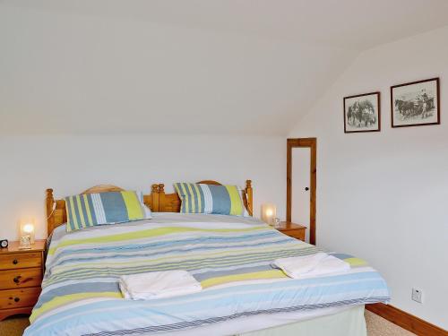 a bedroom with a large bed with blue and yellow stripes at Rathlin Coach House in Comrie