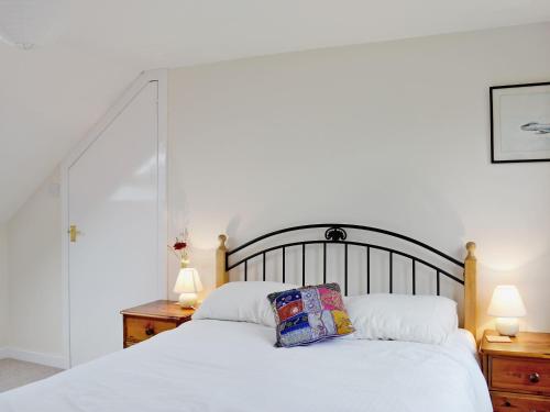 um quarto com uma grande cama branca e 2 candeeiros em Shore Cottage em Bellochantuy