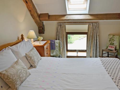 a bedroom with a large white bed with a window at Stonefold Cottage in Waberthwaite
