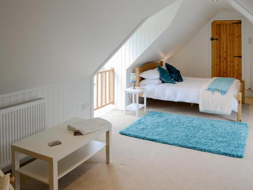 a white bedroom with a bed and a blue rug at Kates Croft in Portgower