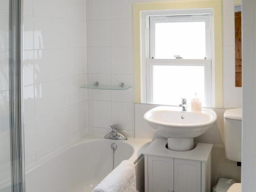 a white bathroom with a sink and a tub and a toilet at Kates Croft in Portgower