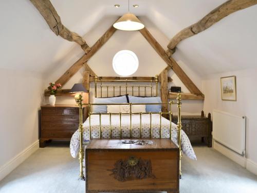 a bedroom with a bed and a ceiling with beams at The Coach House in Aston Cantlow