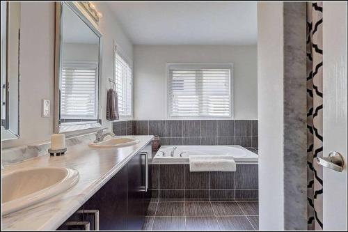 een badkamer met 2 wastafels en een bad bij Living the Dream with Inground Heated Pool, Hot Tub, & Beach in Cobourg