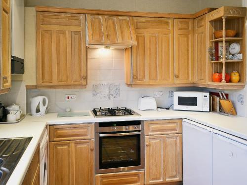 a kitchen with wooden cabinets and a stove top oven at The Old School House in Tideswell
