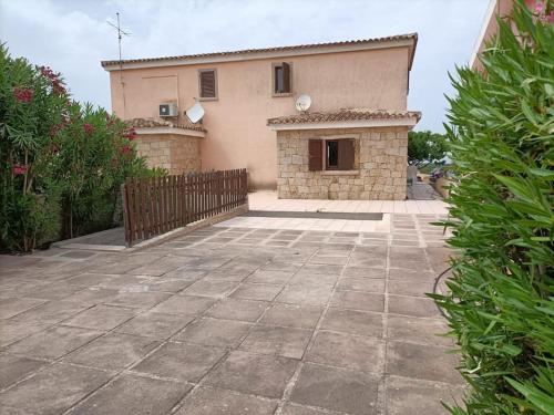a house with a fence and a stone patio at casa a pochi minuti dalla spiaggia di vignola in Vignola Mare