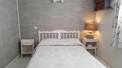 - une petite chambre avec un lit blanc et 2 tables de chevet dans l'établissement Gite bosi tanneron, à Tanneron