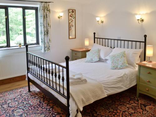 1 dormitorio con 1 cama con sábanas y almohadas blancas en Woodpecker Cottage, en Haydon